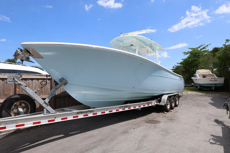 Slide: The Image of 2019 Cobia 320 Center Console boat on trailer under clear blue sky. - 4