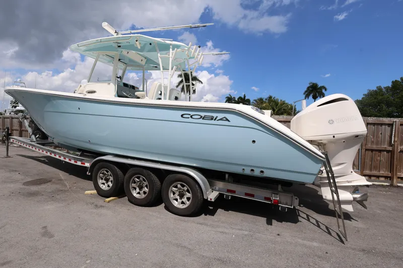 Slide: The Image of 2019 Cobia 320 Center Console boat on trailer, parked outdoors under a cloudy sky. - 5