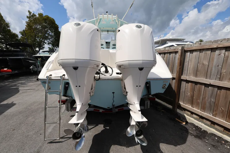 Slide: The Image of 2019 Cobia 320 Center Console boat with dual outboard engines, parked outdoors. - 6