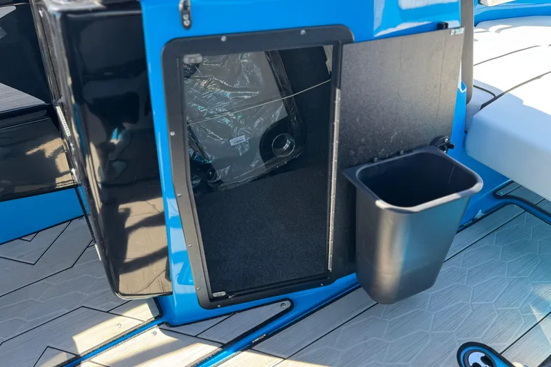 Slide: The Image of 2023 Yamaha Boats 222XD storage compartment with trash bin on deck. - 26