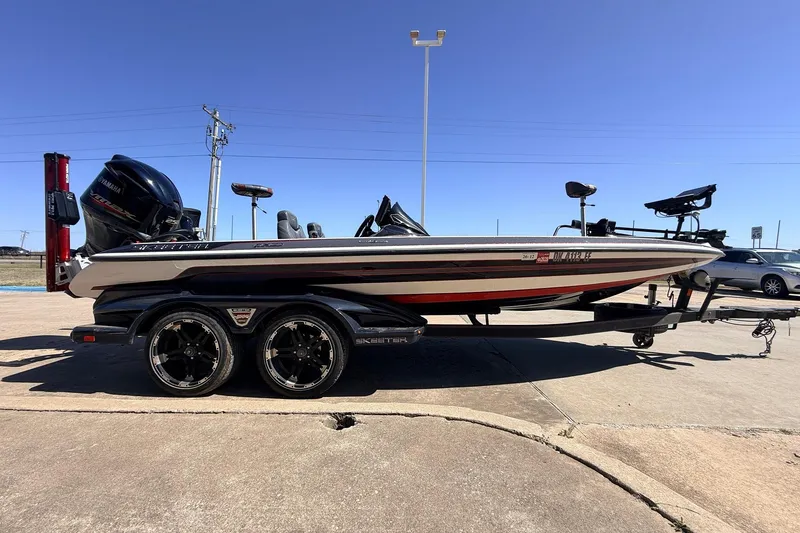 Slide: The Image of 2019 Skeeter FX21 Apex bass boat on trailer, parked outdoors under clear blue sky. - 4
