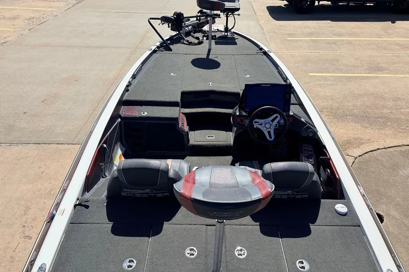 Slide: The Image of 2019 Skeeter FX21 Apex fishing boat with advanced dashboard and seating, parked on concrete. - 8