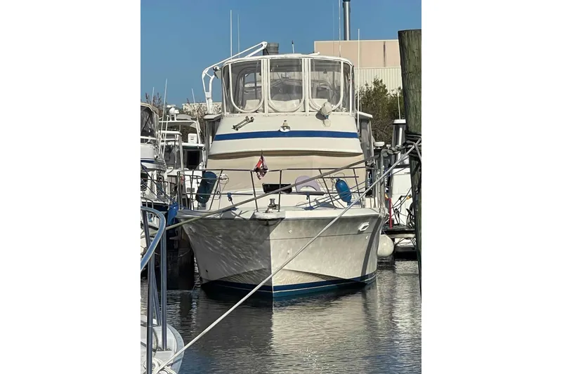 Slide: The Image of 1987 Chris-Craft 426 Catalina interior with white seating and helm chairs in a marina setting. - 32