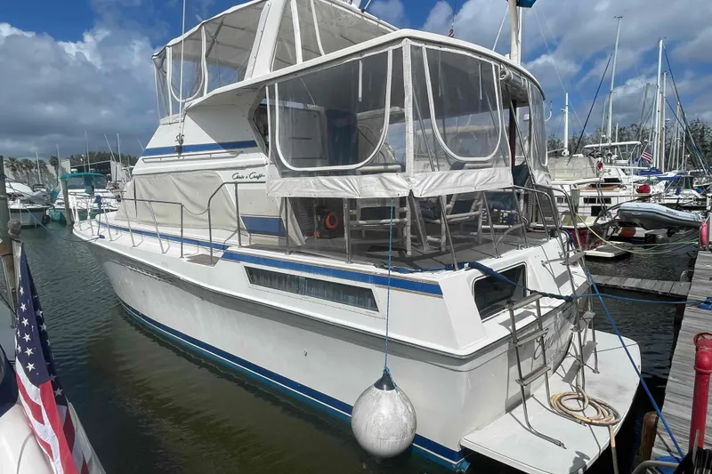 Slide: The Image of 1987 Chris-Craft 426 Catalina yacht docked, featuring spacious deck and flybridge under clear blue sky. - 39