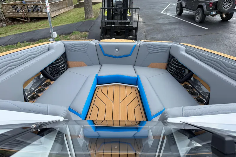 Slide: The Image of 2026 Nautique Super Air Nautique G25 boat interior with gray and blue seating, cup holders. - 18