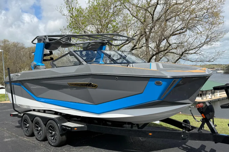 Slide: The Image of 2026 Nautique Super Air Nautique G25 boat on trailer, gray and blue design. - 7