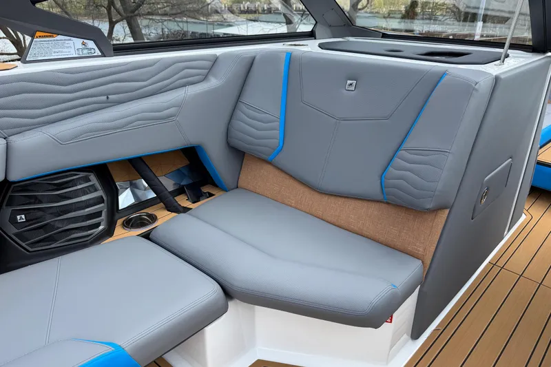 Slide: The Image of 2026 Nautique Super Air Nautique G25 interior with gray and blue seating, speaker, and cup holder. - 21