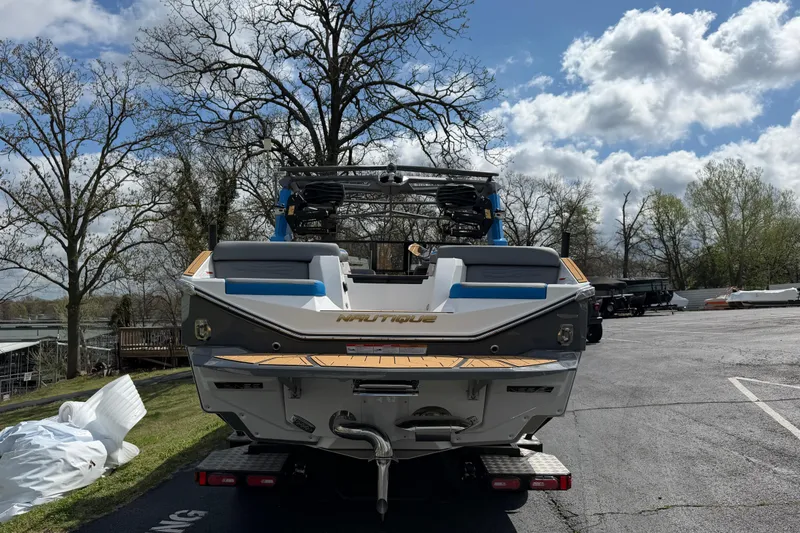 Slide: The Image of 2026 Nautique Super Air Nautique G25 boat on trailer, parked outdoors under cloudy sky. - 9