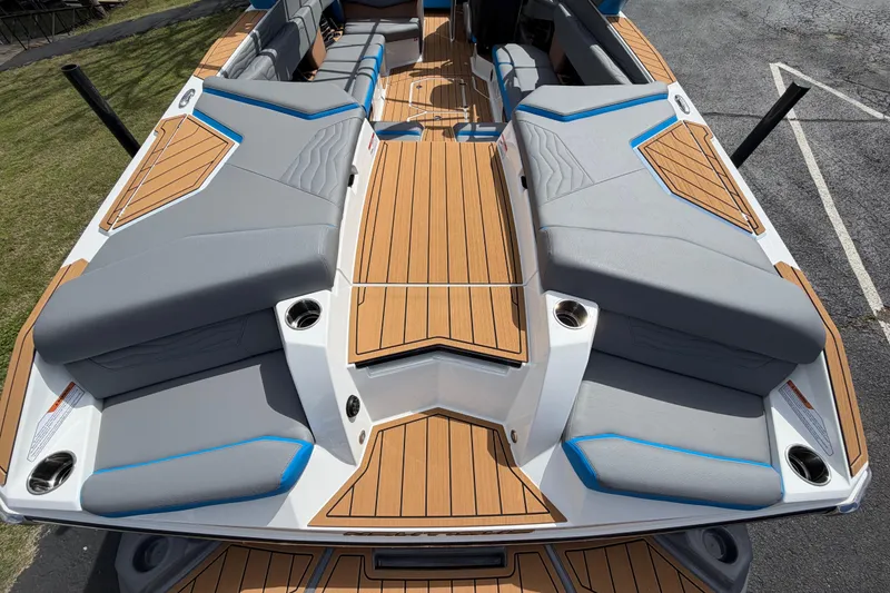 Slide: The Image of 2026 Nautique Super Air Nautique G25 boat interior with gray and blue seating, teak flooring. - 16