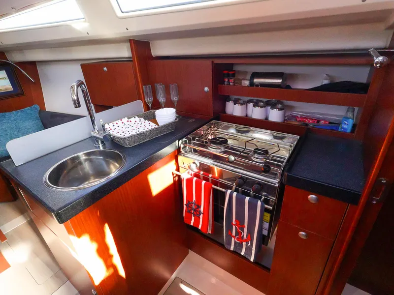 Slide: The Image of 2018 Hanse 315 yacht kitchen with sink, stove, and wooden cabinetry. - 16