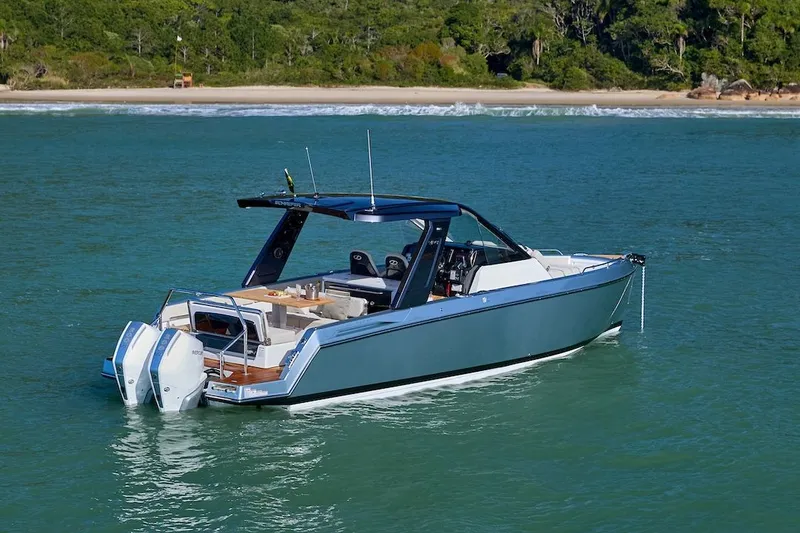 Slide: The Image of Schaefer V34 2027 motorboat on calm waters near a green coastline. - 5