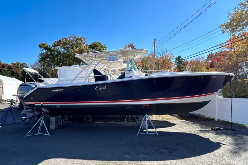 The Image of 2014 Pursuit ST 310 Sport boat on display, blue hull, for sale sign visible. - 0