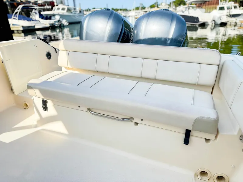 Slide: The Image of 2014 Pursuit ST 310 Sport boat with cushioned seating and twin engines at a marina. - 11
