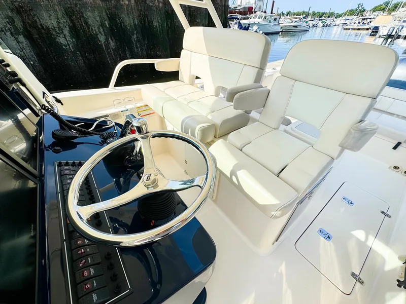 Slide: The Image of 2014 Pursuit ST 310 Sport boat interior with steering wheel and white seating. - 14