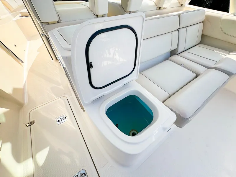 Slide: The Image of 2014 Pursuit ST 310 Sport boat interior with open storage compartment and cushioned seating. - 20