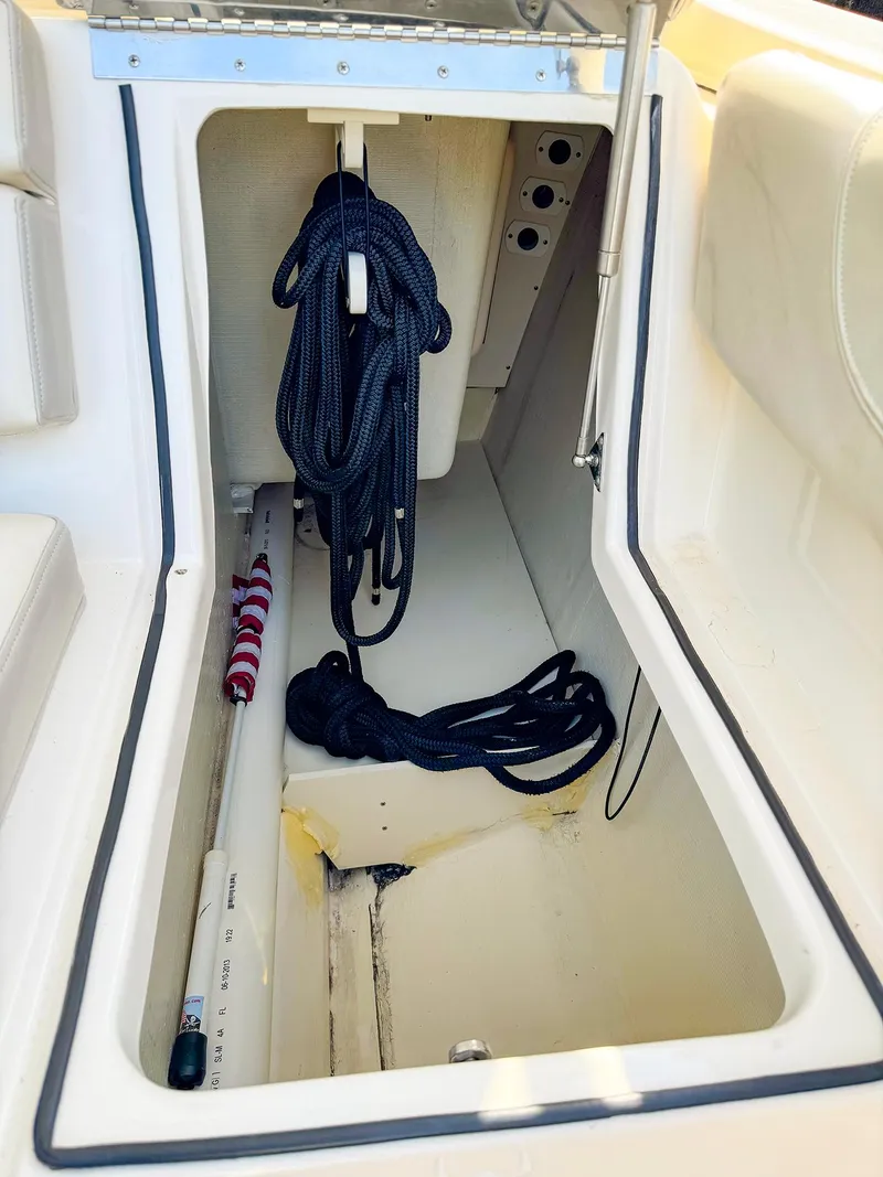 Slide: The Image of Open storage compartment on 2014 Pursuit ST 310 Sport boat with ropes inside. - 23
