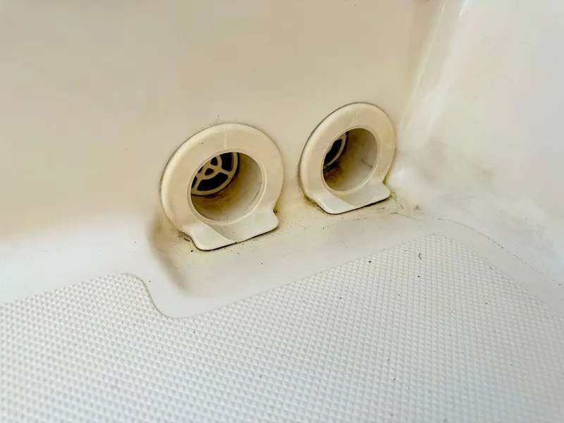 Slide: The Image of 2014 Pursuit ST 310 Sport boat drain plugs on textured surface. - 25