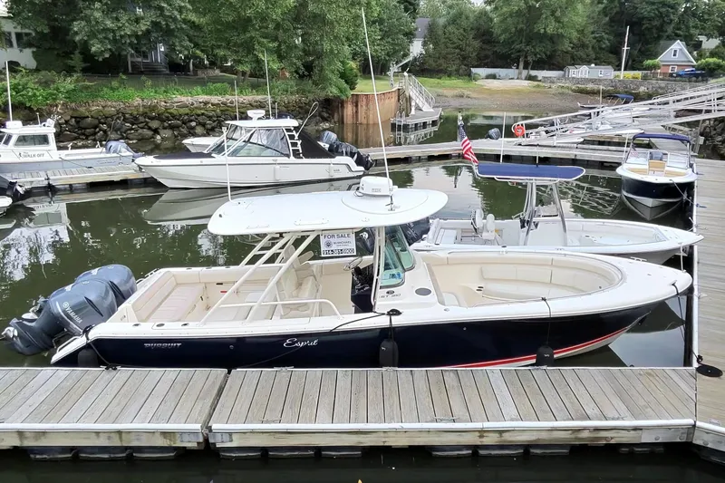 Slide: The Image of 2014 Pursuit ST 310 Sport boat docked, for sale sign visible, surrounded by other boats. - 1