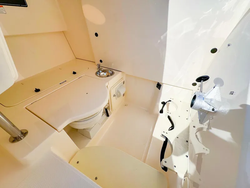 Slide: The Image of Interior of 2014 Pursuit ST 310 Sport boat, featuring a compact bathroom with sink and toilet. - 35