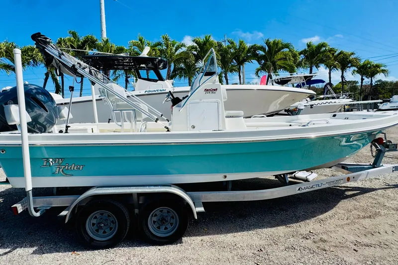Slide: The Image of 2023 KenCraft 219 Bay Rider boat on trailer, parked outdoors with palm trees in background. - 5