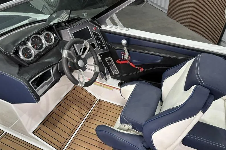 Slide: The Image of 2019 MasterCraft XT22 boat interior with steering wheel, dashboard, and blue-white seating. - 6