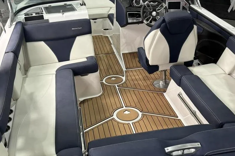 Slide: The Image of 2019 MasterCraft XT22 boat interior with navy and white seating, teak flooring, and modern dashboard. - 7