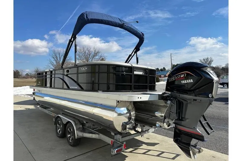 Slide: The Image of 2022 Bennington 24 SXSR Tritoon with Yamaha Vmax 250 SHO on trailer, under blue sky. - 10