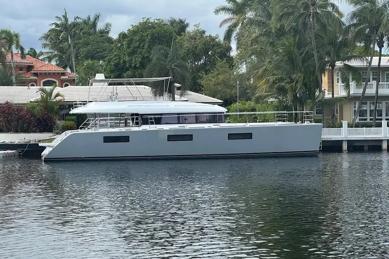 Slide: The Image of Luxury 2015 Lagoon yacht docked by waterfront homes, surrounded by lush palm trees. - 2