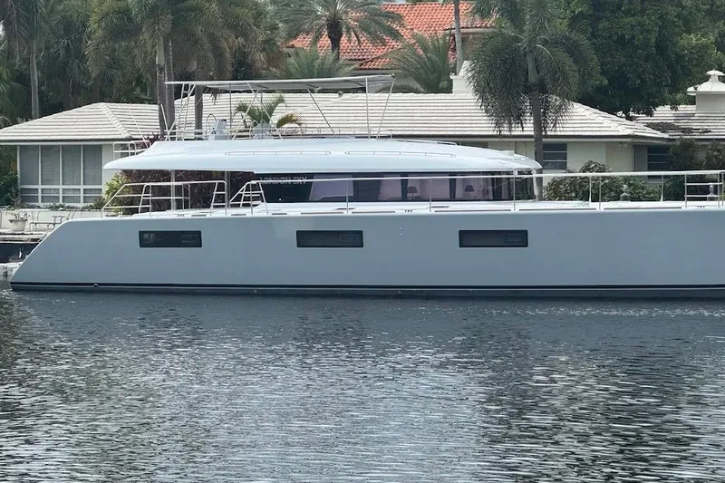 Slide: The Image of 2015 Lagoon catamaran docked by waterfront home, surrounded by palm trees. - 27