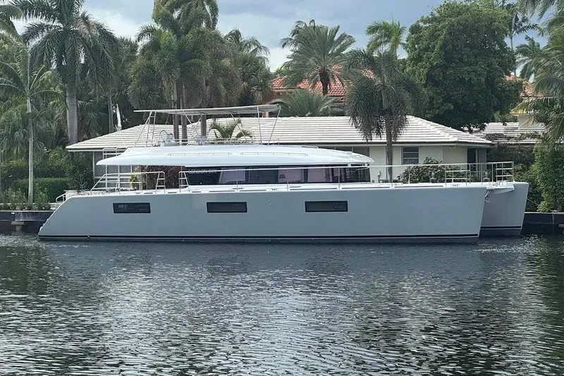 Slide: The Image of 2015 Lagoon catamaran docked by a waterfront home, surrounded by lush palm trees. - 30