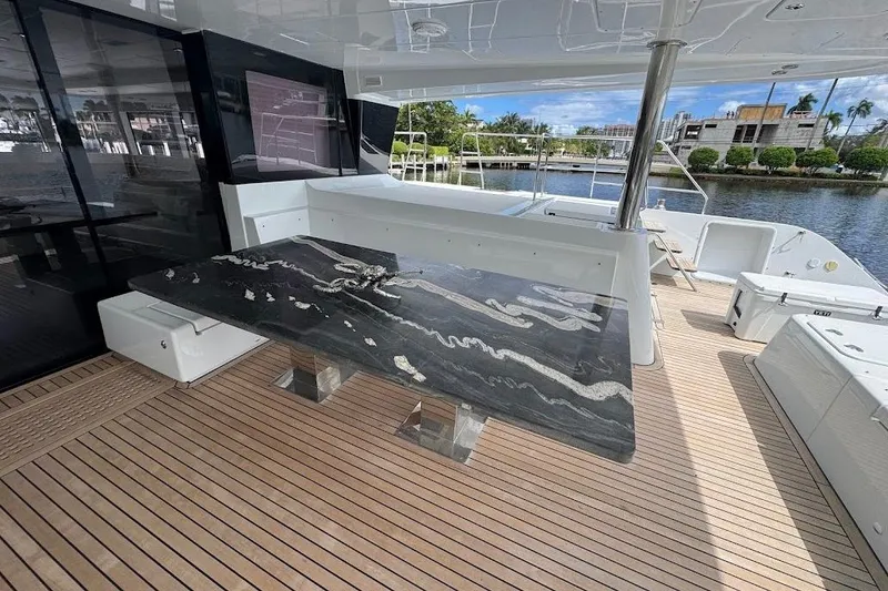 Slide: The Image of Luxurious 2015 Lagoon yacht deck with elegant black marble table and scenic waterfront view. - 9
