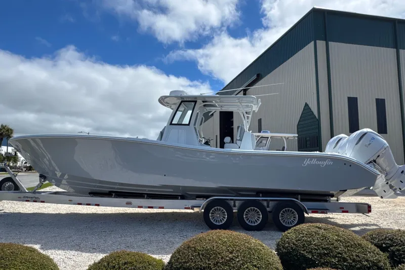 Slide: The Image of 2026 Yellowfin 36 Offshore boat on trailer, parked near a large building under a cloudy sky. - 6