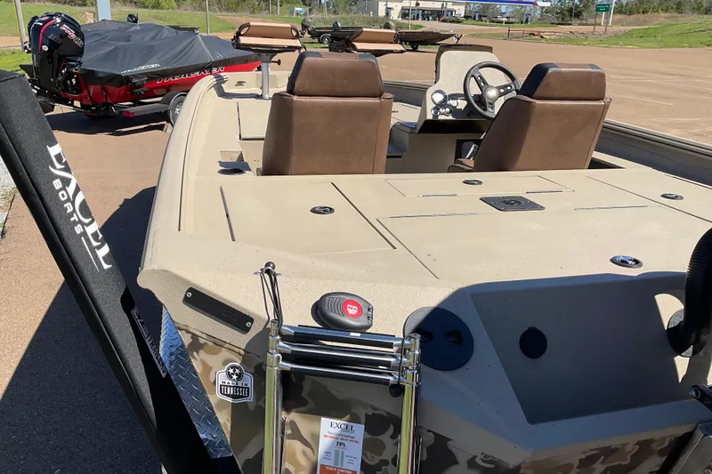 Slide: The Image of 2026 Excel EX 203 boat with camo design, dual seats, and steering wheel, parked outdoors. - 3