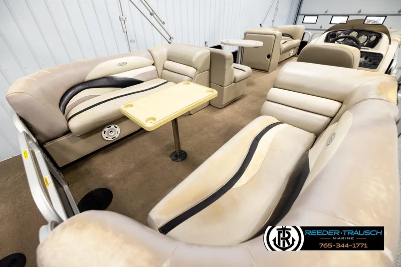Slide: The Image of Interior of a 2011 Godfrey SW2486 pontoon boat with beige seating and tables. - 12