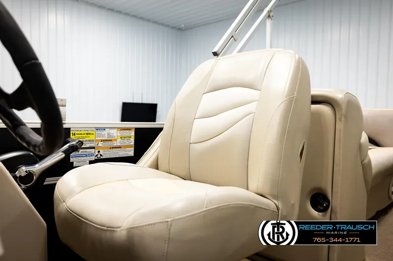 Slide: The Image of Cream leather seat in a 2011 Godfrey SW2486 boat, featuring steering wheel and safety labels. - 36