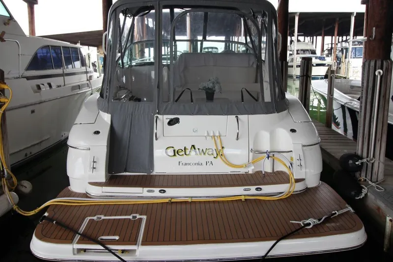 Slide: The Image of 2004 Cruisers Yachts 320 Express docked, featuring a covered cockpit and wooden deck. - 3