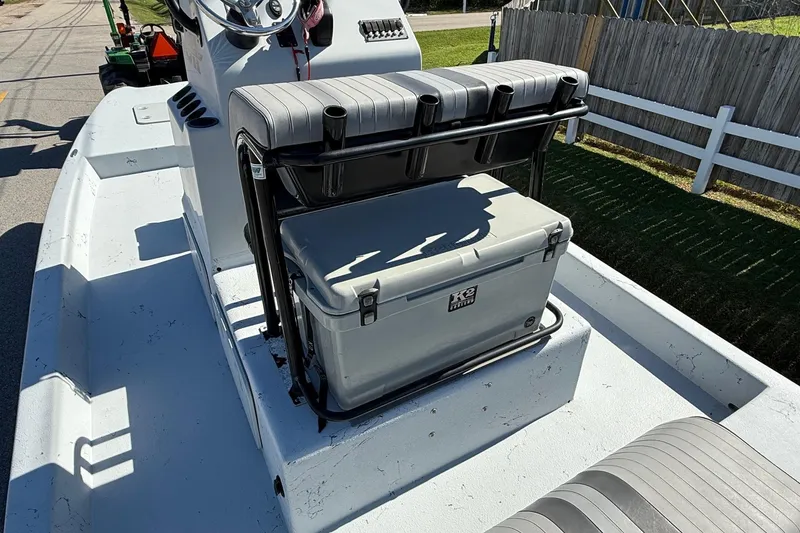 Slide: The Image of JH Performance boat with seating and cooler on deck, parked near a wooden fence. - 8