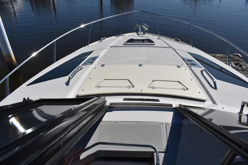 Slide: The Image of 2020 Regal 35 Sport Coupe boat deck with open hatch, docked on calm water. - 24