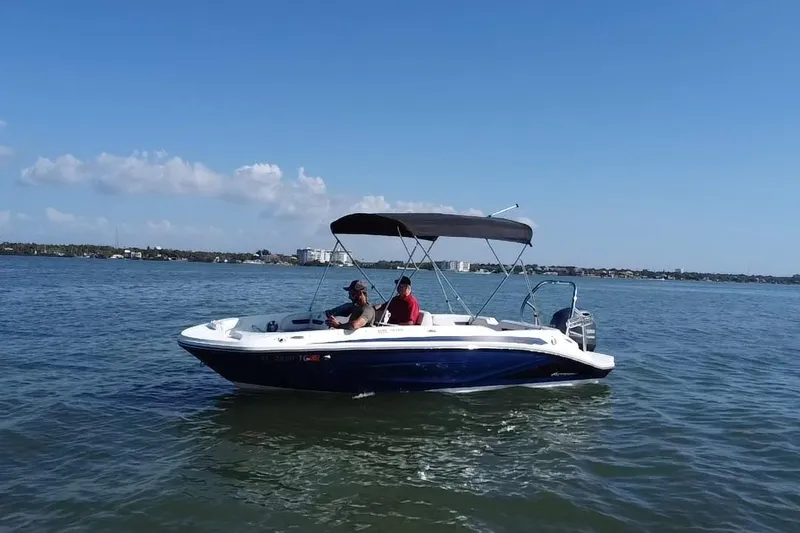 Slide: The Image of 2022 Hurricane SunDeck Sport 185 OB boat cruising on calm waters under a clear blue sky. - 19