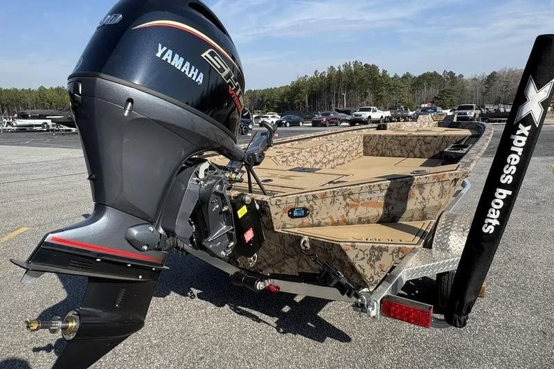Slide: The Image of 2026 Xpress X18DB boat with Yamaha engine, camo design, parked outdoors. - 4