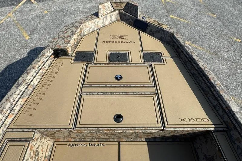Slide: The Image of 2026 Xpress X18DB boat deck with storage compartments and camouflage design. - 9