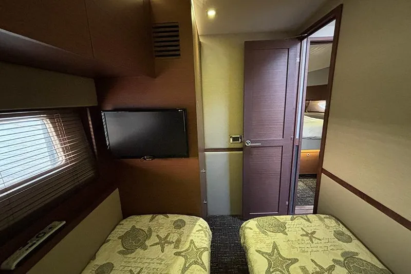 Slide: The Image of 2015 Sea Ray 510 Fly cabin with twin beds, TV, and wooden interior. - 42