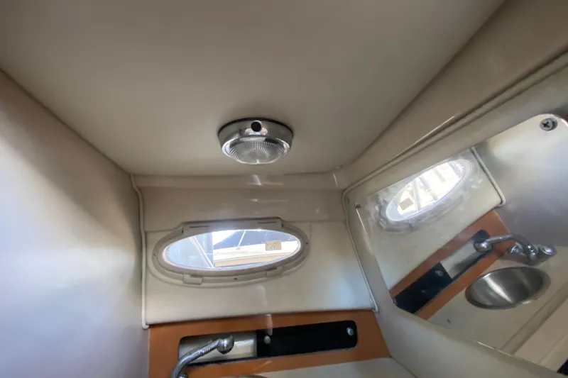 Slide: The Image of 2007 Robalo R265 Walkaround cabin interior with porthole, light fixture, and sink. - 33