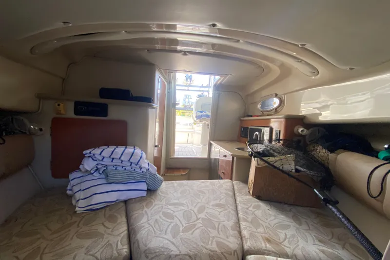 Slide: The Image of 2007 Robalo R265 Walkaround cabin interior with seating, folded towels, and fishing gear. - 34