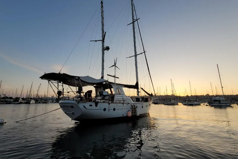 Slide: The Image of 1974 Force Hudson 50 sailboat at sunset in a marina, surrounded by other boats. - 10
