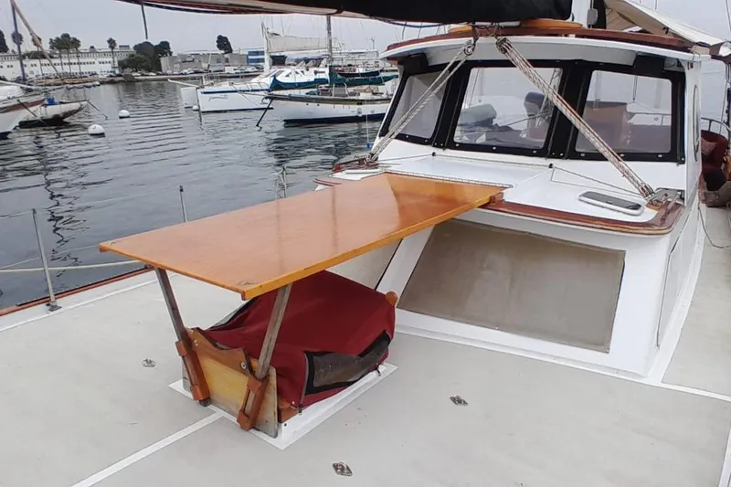 Slide: The Image of 1974 Force Hudson 50 yacht with wooden deck table, docked in marina. - 19