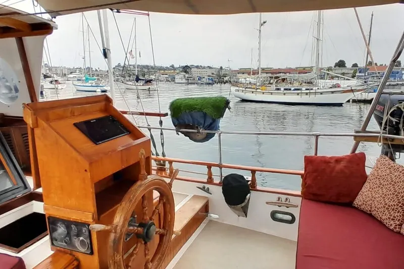 Slide: The Image of 1974 Force Hudson 50 yacht interior with wooden helm, marina view, and cozy seating. - 37