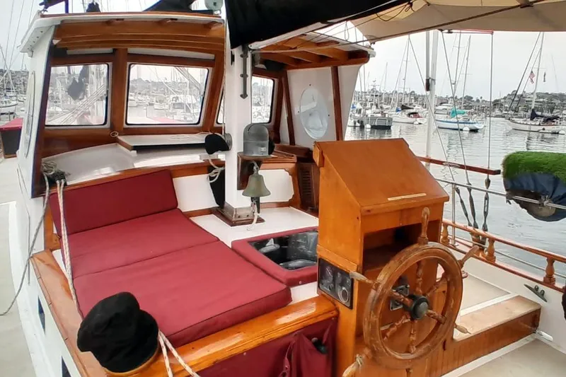 Slide: The Image of 1974 Force Hudson 50 sailboat cockpit with wooden helm, red cushions, and marina view. - 39
