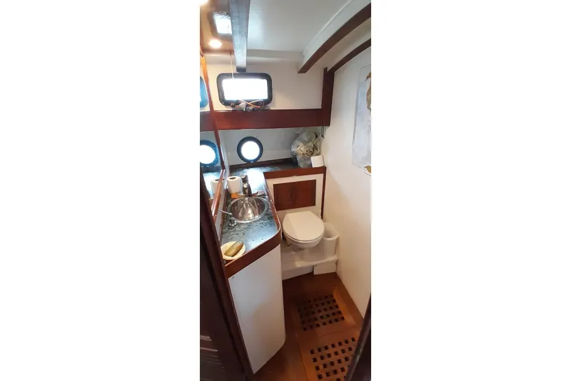 Slide: The Image of 1974 Force Hudson 50 yacht bathroom with wooden accents and porthole windows. - 55