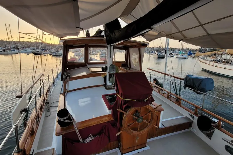 Slide: The Image of 1974 Force Hudson 50 sailboat docked at marina during sunset, showcasing wooden deck and helm. - 9